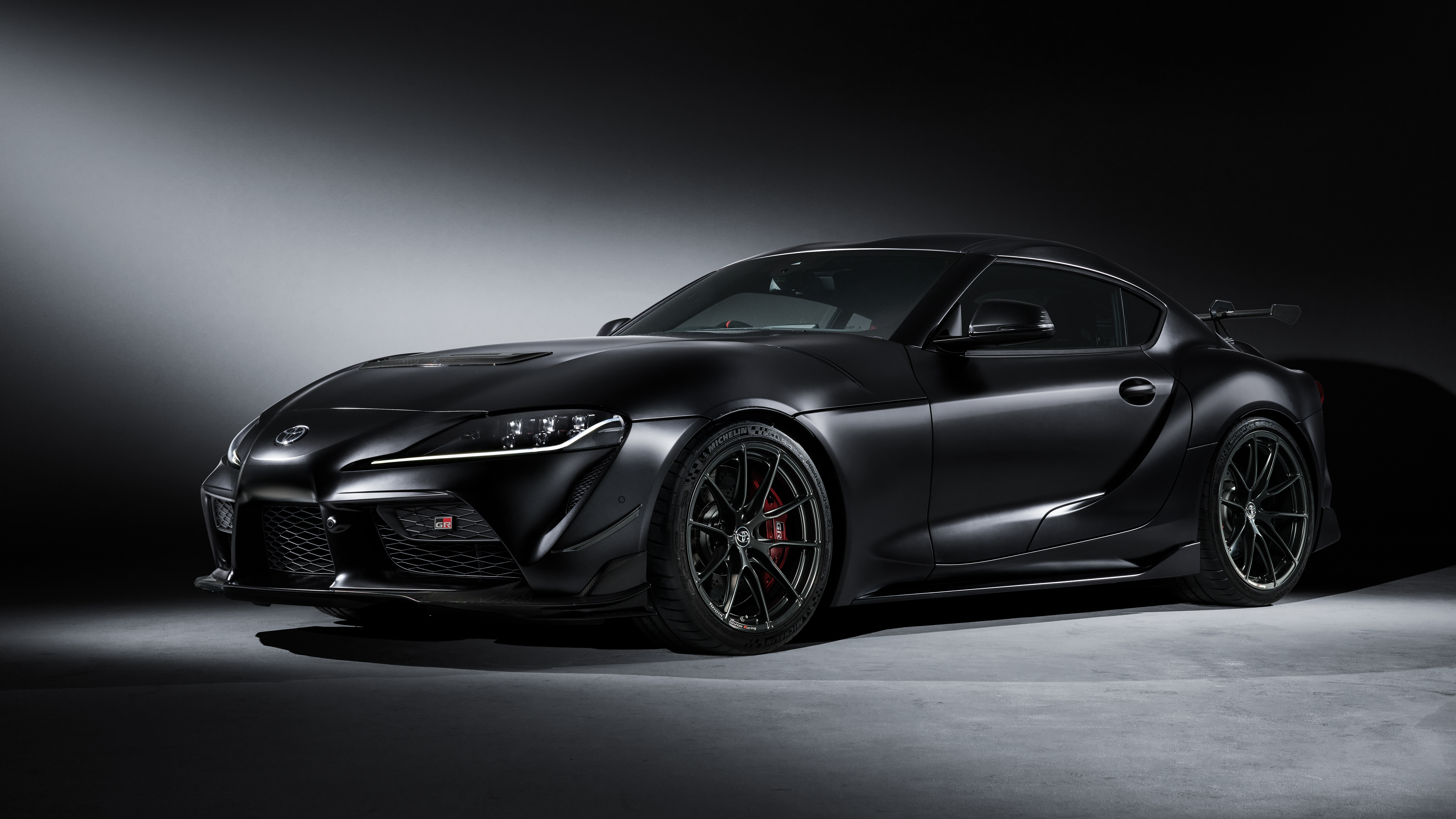 Black GR Supra in a dark studio under a soft spotlight