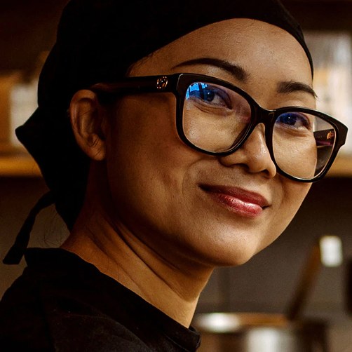 Cheffe Yūgen souriante en toque noire