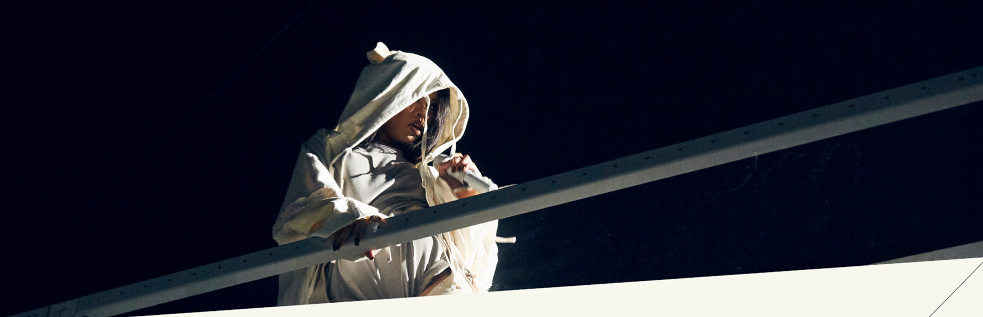 Rihanna en sweat à capuche blanc, penchée sur une rambarde