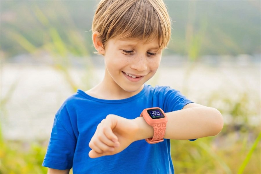 Petit garçon souriant qui regarde la montre KiddoWatch à son poignet