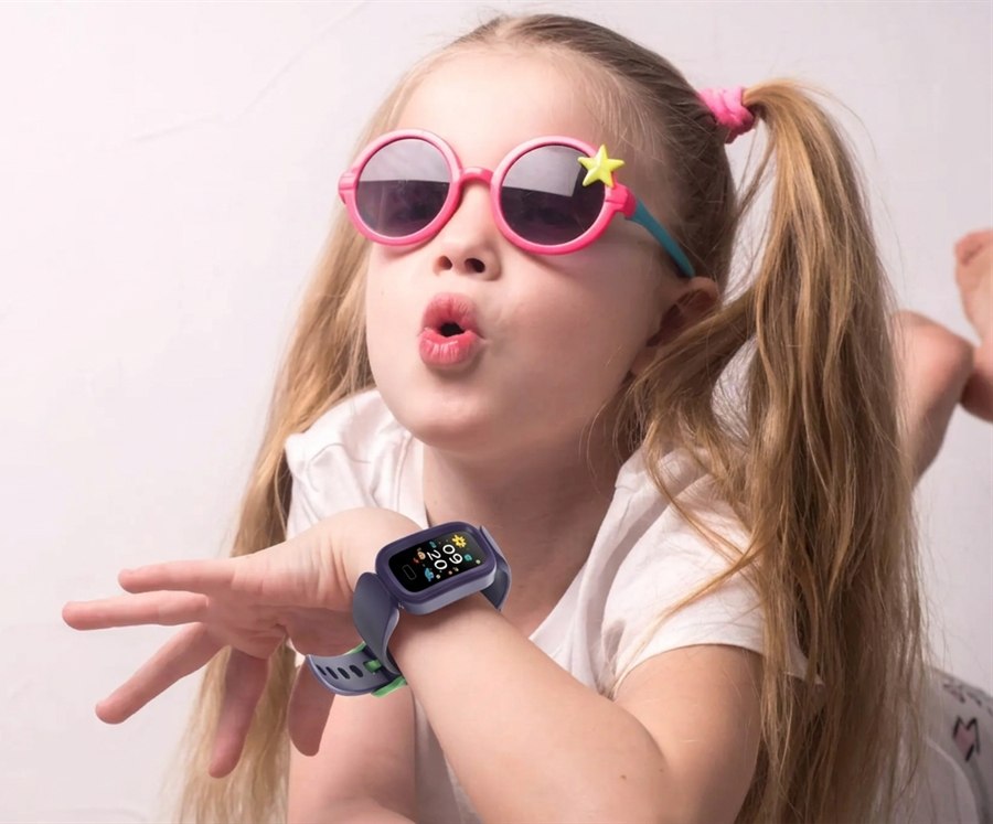 Petite fille avec des lunettes roses montrant sa montre KiddoWatch au poignet